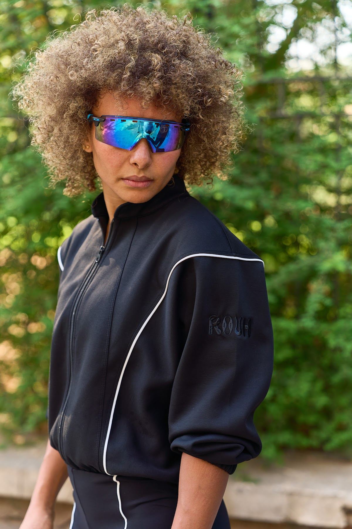Close-up in a black zip jacket and blue sunglasses