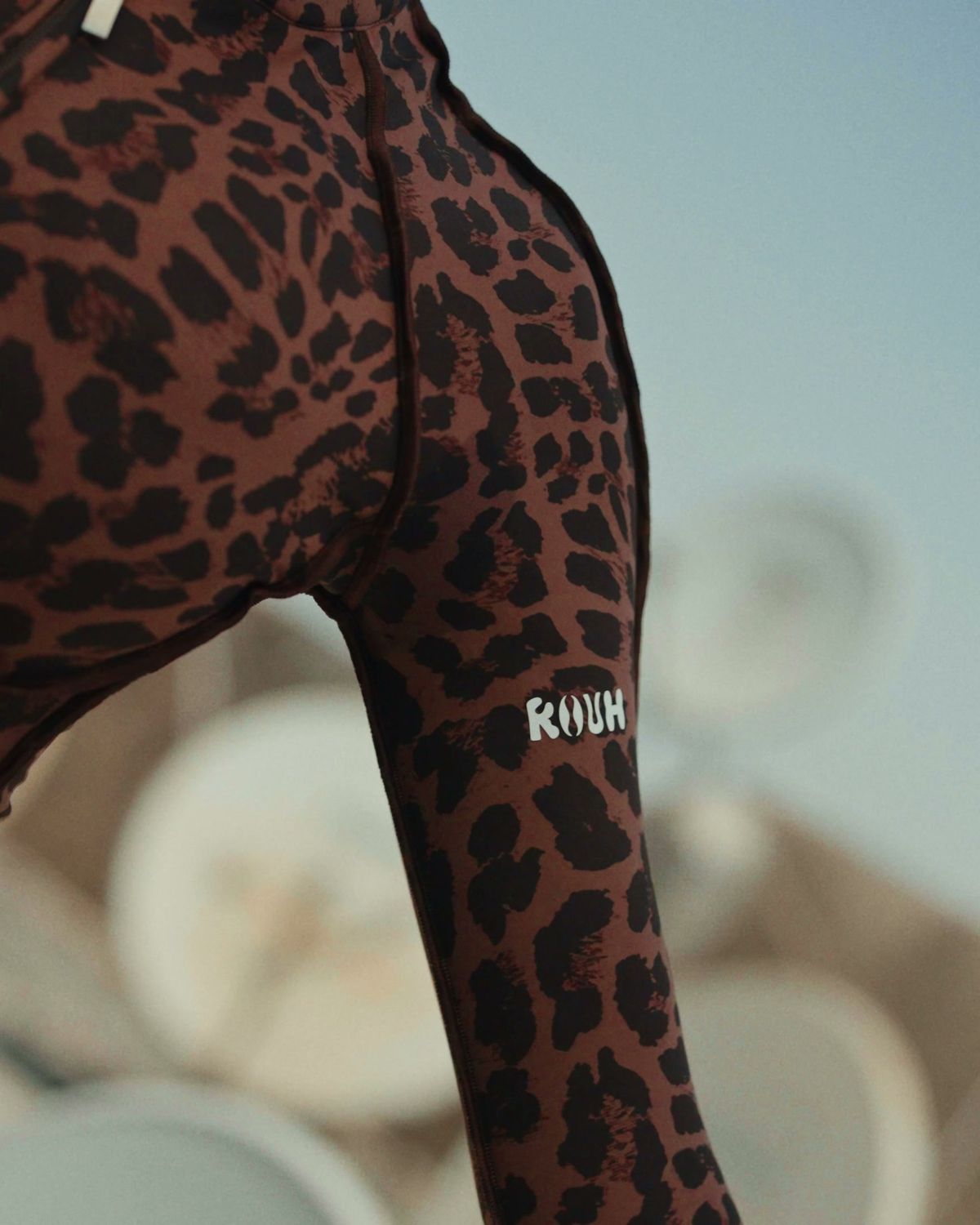 Close-up of a leopard print ROUH suit with the ROUH label on the leg